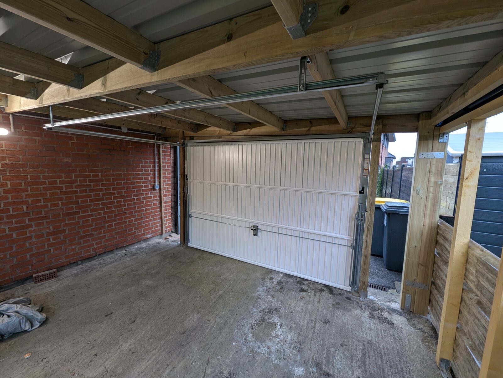 Vue intérieure d'un porte de garage basculante noire de marque Novoferm posée sur carport existant en bois à Neuville en Ferrain (Nord) .jpg