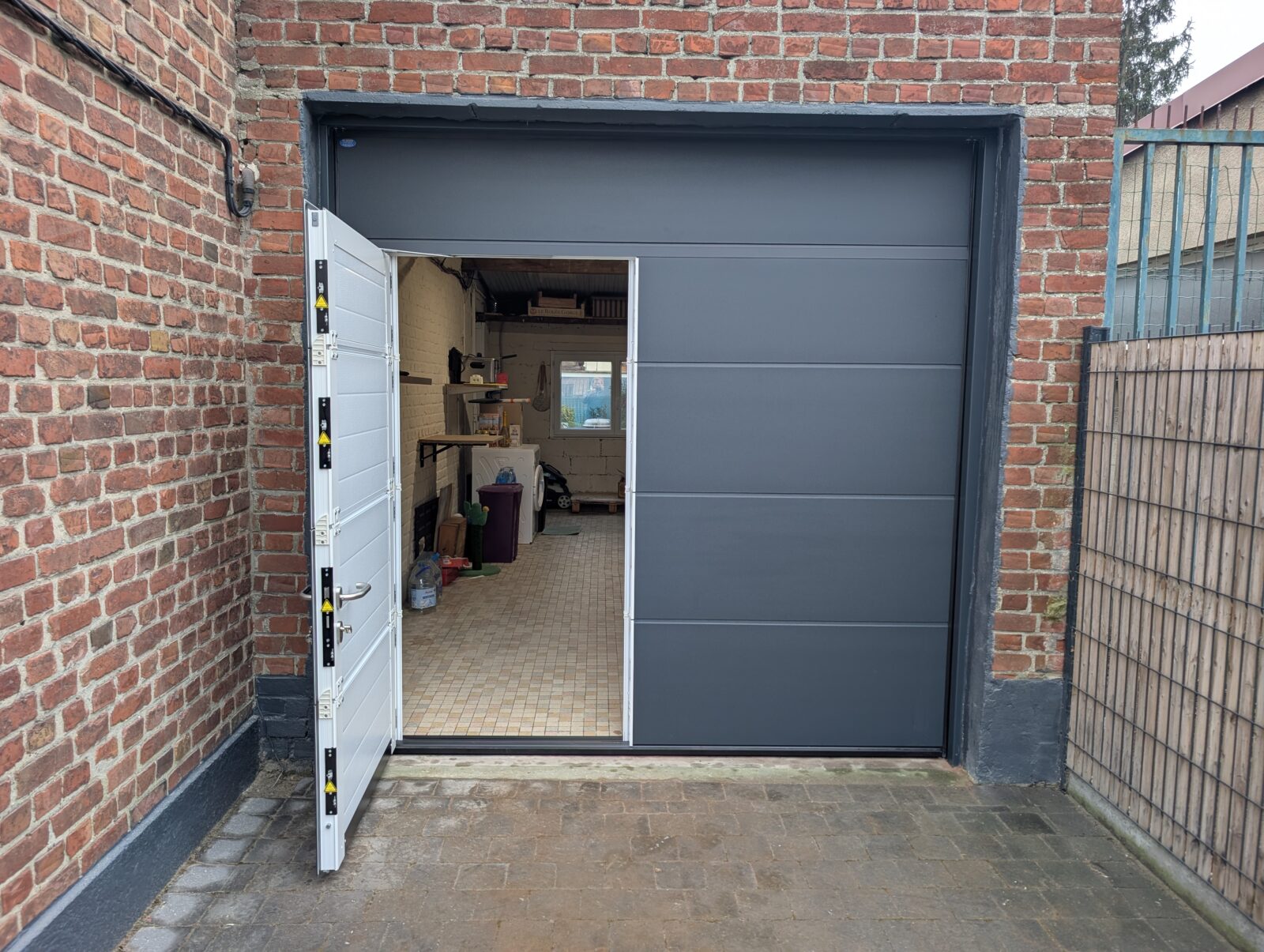 Dans le cadre d'un remplacement, installation d'une porte sectionnelle Novoferm avec portillon intégré fermeture 5 points à Ronchin dans la métropole lilloise (Nord).