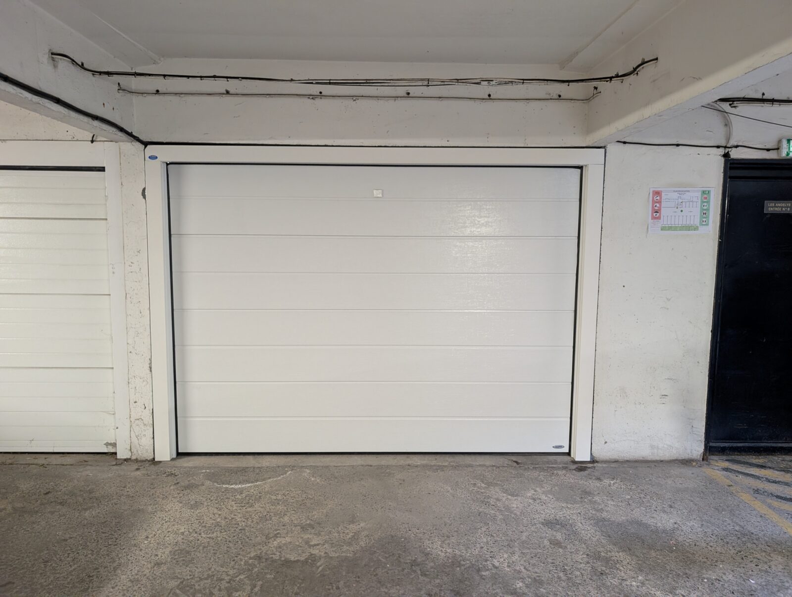 APRÈS - Remplacement d'une porte basculante par une porte sectionnelle Novoferm motorisée avec télécommande. Pose sur précadre à La Madeleine dans le Nord.